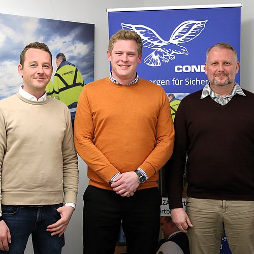 Drei M&auml;nner stehen nebeneinander. Im Hintergrund ist ein Condor auf einer Leinwand zu sehen sowie ein Bild mit einem Flugzeug.